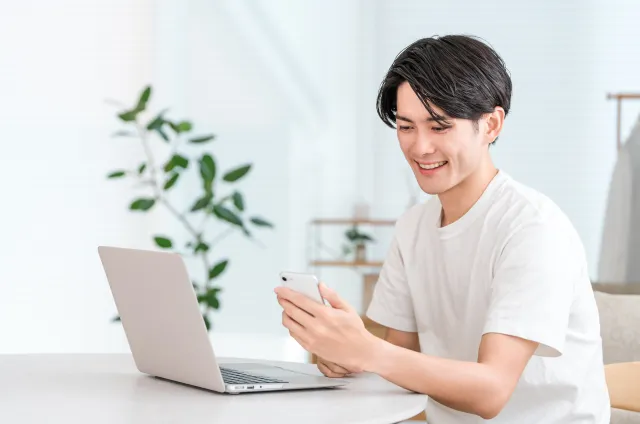 ラップトップとスマホで学ぶ男性